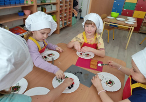 Dzieci ozdabiają swoje "biedronki" z pomidorka szczypiorkiem.